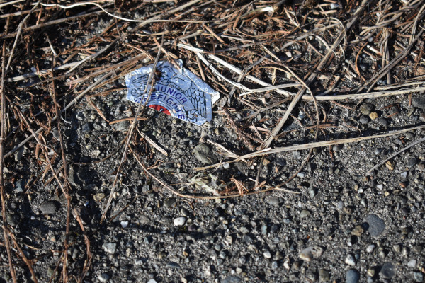 A used sticker that says junior firefighter discarded on the ground.