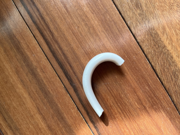 A ceramic mug handle that has broken off a cup.