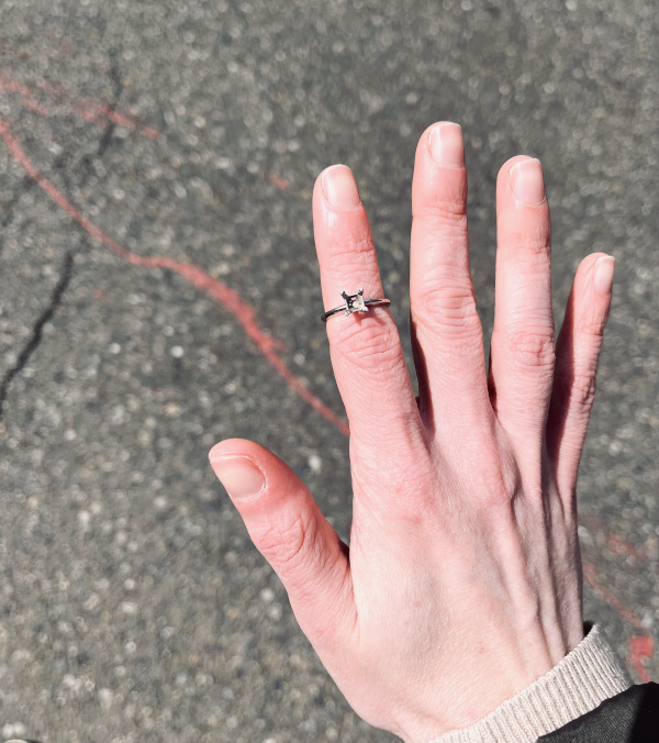 Hand displaying a ring with the stone missing from the setting.